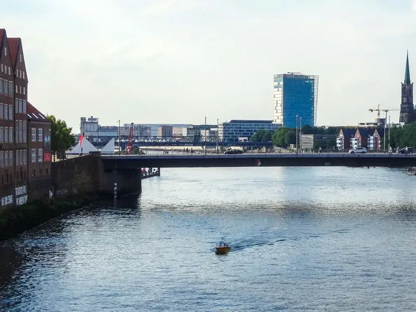 Blick über die Weser auf die Bremer Innenstadt mit Brücke und Hochhaus.